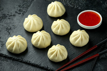 Steamed Buns with duck stuffing, chili sauce on rustic stone board. Asian food