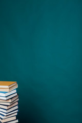 many stacks of educational books for learning preparation for college exams on a green background