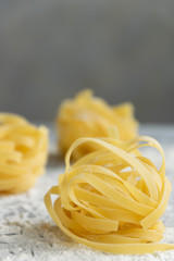 Handmade italian pasta - tagliatelle on grey floury background
