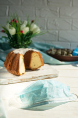 Medical blue protective disposable mask on a background of Easter baking. Protection against viruses. The concept of the celebration of Holy Easter in the context of the coronavirus pandemic.