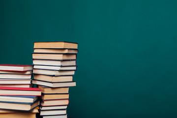 many stacks of educational books for learning preparation for college exams on a green background