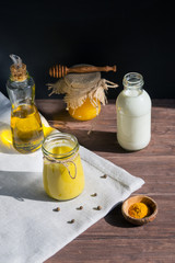 Turmeric-based golden milk healing drink and ingredients on black background. Prevention of diseases and strengthening immunity.