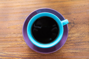 Taza de colores con café sobre mesa de madera