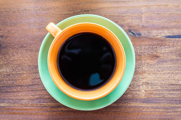 Taza de colores con café sobre mesa de madera