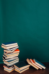many stacks of educational books for learning preparation for college exams on a green background