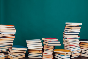 many stacks of educational books for learning preparation for college exams on a green background
