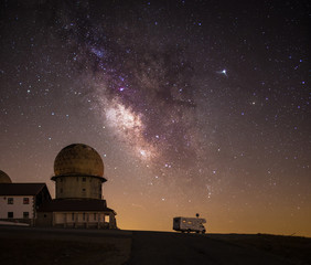 Milky Way galaxy starry sky with caravan on mountain road
