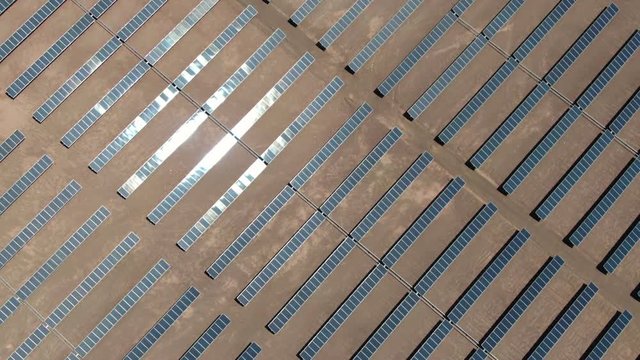 Aerial view of massive Photovoltaic Plant in the middle of the Atacama desert in Chile. Flying over hundreds of rows of solar energy panels on a sunny day, green sustainable energy concept.