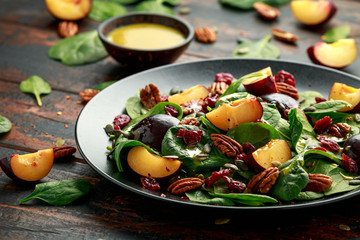 Vegan plums salad with cranberry, pumpkin seed, pecans nuts, spinach and mustard dressing