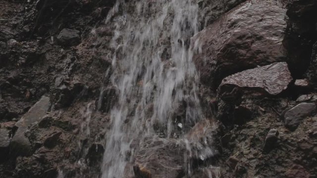 water is running trough big crack in basalt boulder