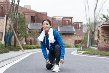 A young Asian woman squatting to tie shoelaces