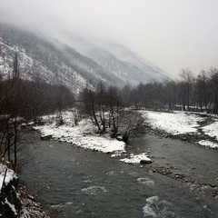 confluence of two rivers in winter. mountains in the fog. forest by the winter river