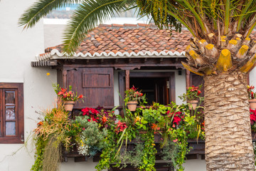 Fototapeta na wymiar Famous ancient colorful balconies decorated with flowers. Santa Cruz - capital city of the island of La Palma, Canary Islands, Spain.