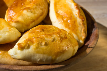 Baked cakes. Yeast baking. Pies with meat, cabbage and mushrooms. Homemade food. Slavic cuisine. Delicious pastries. Ruddy snack. Flour product. Bake in the oven. Junk food.