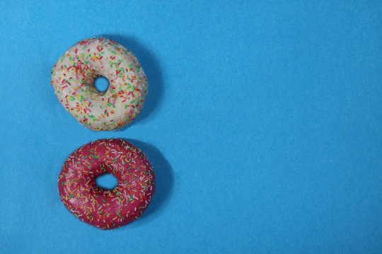 two donuts isolated on blue background flat lay. Horizontal image