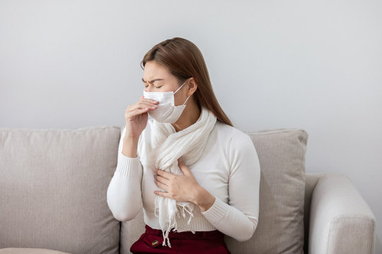 sick woman wearing face protection mask coughing on sofa has fever by coronavirus 2019 or COVID-19 after travel from China,Coronavirus Concept..