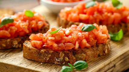 Tomato bruschetta seasoned with basil on a rustic wooden board