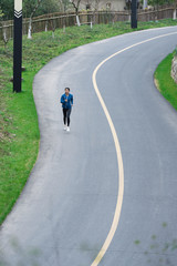 A young Asian woman is running on the road