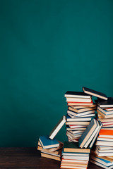 many stacks of educational books for learning preparation for college exams on a green background