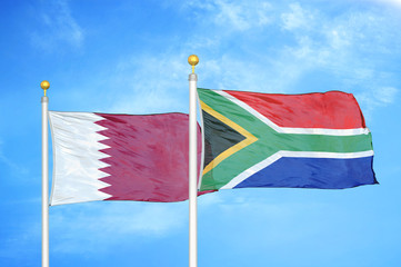 Qatar and South Africa two flags on flagpoles and blue cloudy sky