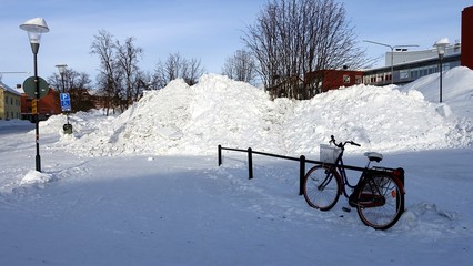 a bicycle parked in one of the snowy streets in the center of Kiruna in Sweden