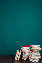 many stacks of educational books for learning preparation for college exams on a green background