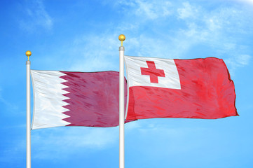 Qatar and Tonga two flags on flagpoles and blue cloudy sky