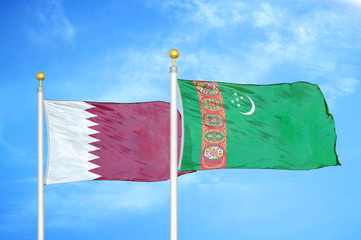 Qatar and Turkmenistan two flags on flagpoles and blue cloudy sky