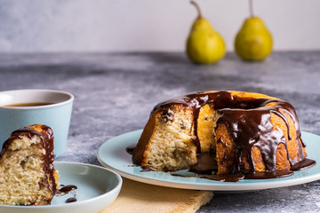 Cake with pouring chocolate, a cup of coffee on blurred bokeh background.