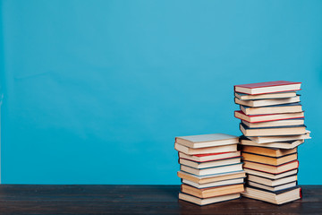 many stacks of educational books for learning preparation for college exams on a blue background