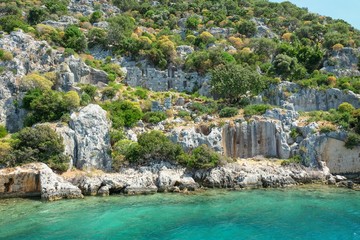 Fototapeta na wymiar Weathered ruins of famous ancient underwater town Sunken City on Kekova island, in mediterranean coastline of Antalya province,Turkey. Popular tourist places in Turkey.