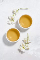 Fototapeta na wymiar two bowls with green tea on a white background and jasmine, vertical