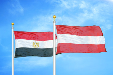 Egypt and Austria  two flags on flagpoles and blue cloudy sky