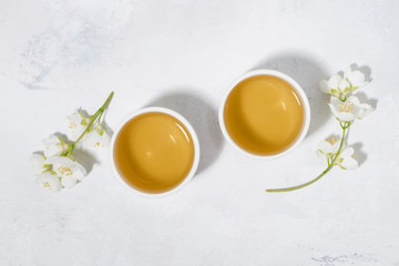 two bowls with green tea on a white background and jasmine