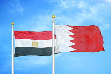 Egypt and Bahrain  two flags on flagpoles and blue cloudy sky