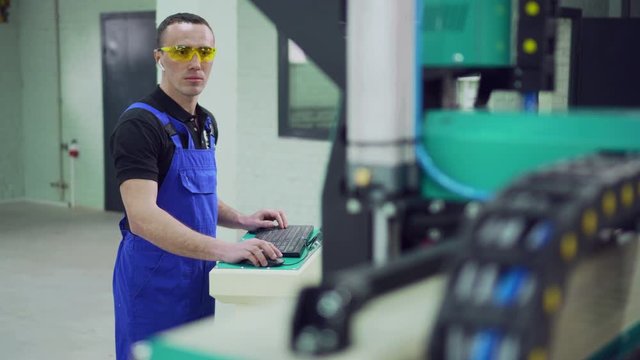 A male operator controls the CNC machine while standing at the control panel.