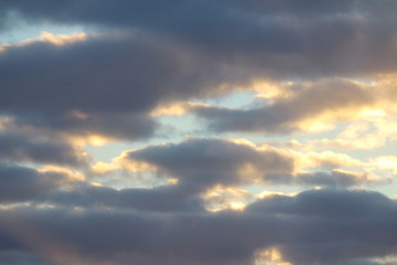 Clouds in the blue sky at sunset or dawn backlit by the sun. Place for text and design.