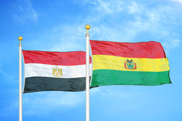 Egypt and Bolivia  two flags on flagpoles and blue cloudy sky