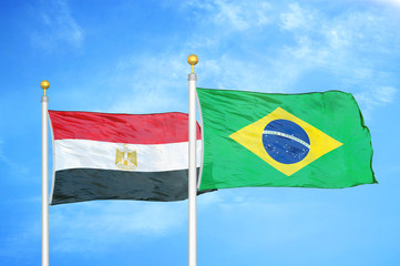 Egypt and Brazil  two flags on flagpoles and blue cloudy sky