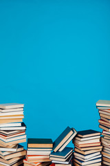 many stacks of educational books for learning preparation for college exams on a blue background