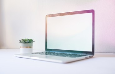 Laptop mockup on work desk in sunset. Close-up laptop with flowers, coffee, croissant, with morning light. Modern, thin laptop design.White. Isolated screen for mockup. Laptop profile. Home office