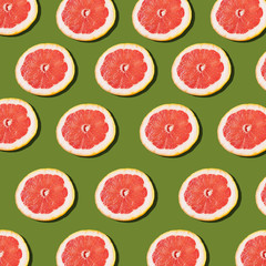 Pink ripe grapefruit slices on the green background pattern.