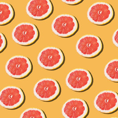 Fototapeta na wymiar Pink ripe grapefruit slices on the orange background pattern.