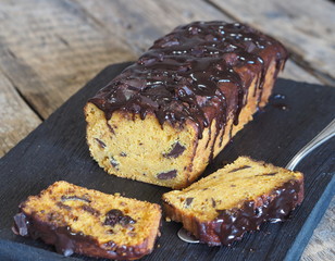 Festive chocolate soft pumpkin muffin, poured with chocolate icing, on a wooden ancient background.