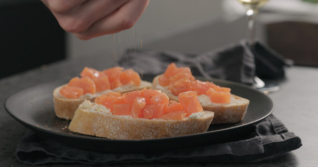 seasoning bruschetta with cream cheese and salted trout on black plate