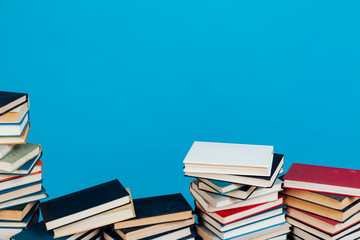 many stacks of educational books for learning preparation for college exams on a blue background