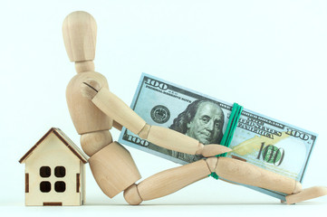 wooden mannequin and house with money, the concept of saving in a crisis