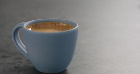 blue cup with fresh espresso on concrete surface