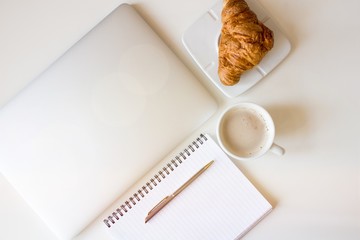 Top view Laptop on work desk in sunset. Close-up laptop, blank notes, pen, coffee, with morning light. Modern, thin laptop design.White. Isolated screen for mockup. Home office