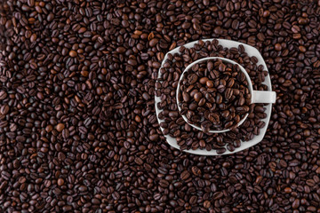 White mug and saucer next to roasted coffee beans everywhere, inside the mug and a lot around it. Great for going to a cafe, restaurant, cafeteria menu or as a sign